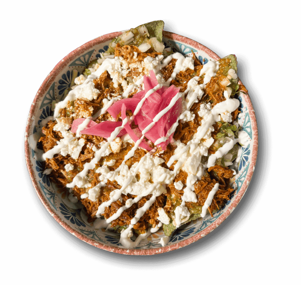 Un plato hondo con chilaquiles, nachos con pollo, queso